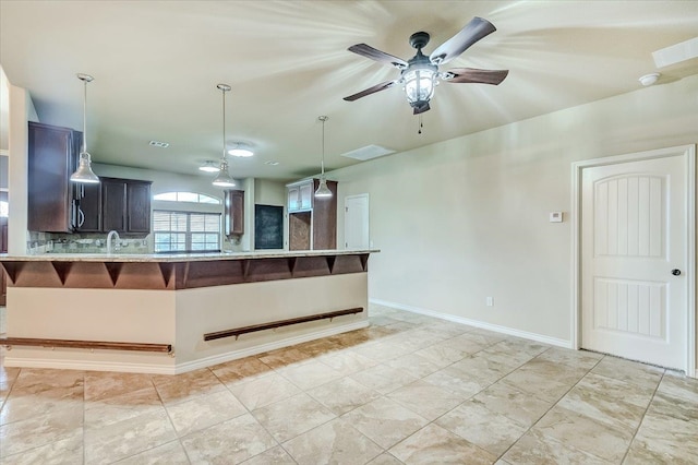 kitchen featuring kitchen peninsula, a kitchen bar, tasteful backsplash, ceiling fan, and sink