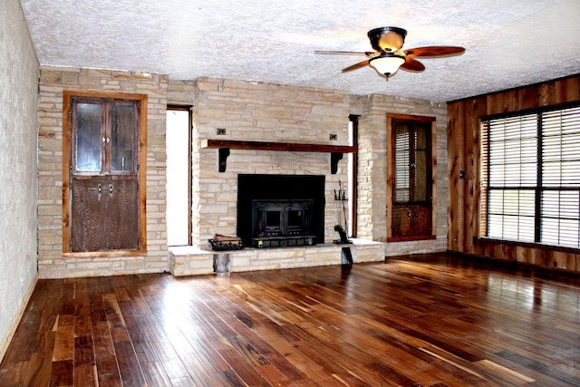 unfurnished living room featuring ceiling fan, a fireplace, wood-type flooring, and a textured ceiling