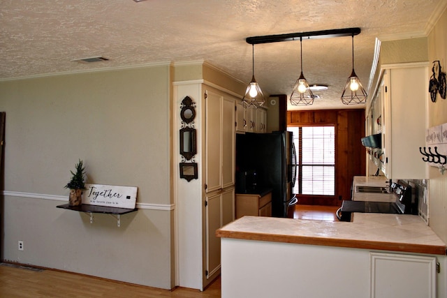 kitchen featuring black fridge, kitchen peninsula, hanging light fixtures, and ornamental molding