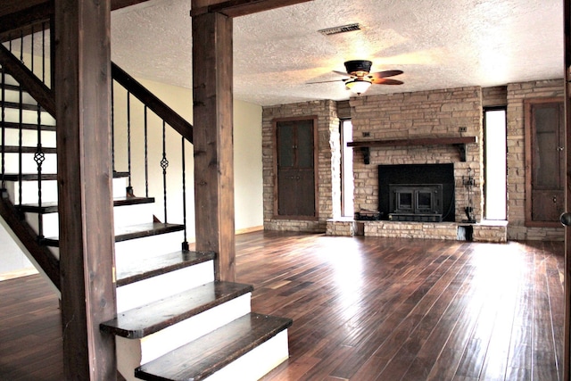 unfurnished living room featuring a fireplace, a textured ceiling, hardwood / wood-style flooring, and ceiling fan