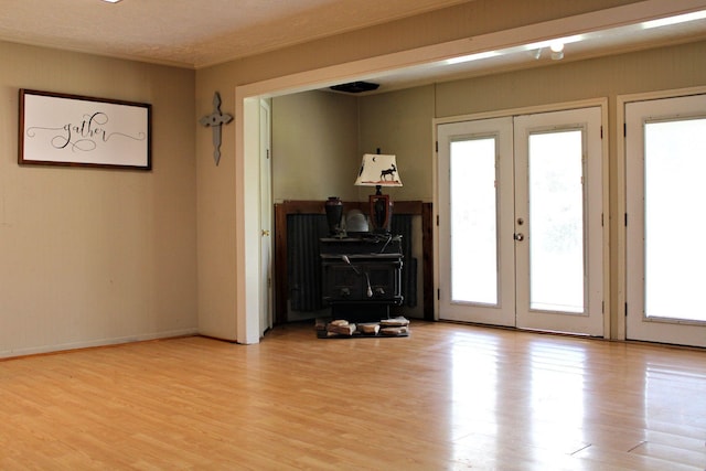 doorway to outside featuring french doors, light wood-type flooring, a textured ceiling, and ornamental molding