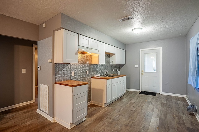 kitchen featuring wood counters, tasteful backsplash, a textured ceiling, wood-type flooring, and white cabinets