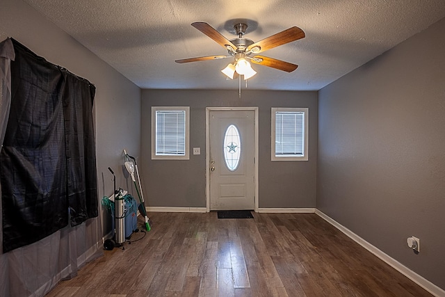 foyer with a textured ceiling, ceiling fan, and dark wood-type flooring