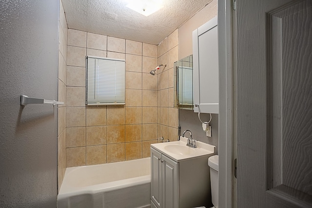 full bathroom featuring vanity, toilet, a textured ceiling, and tiled shower / bath