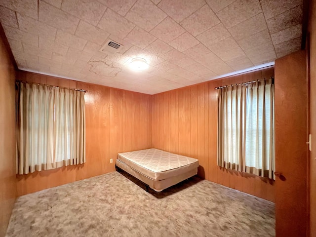 unfurnished bedroom featuring wood walls and carpet floors