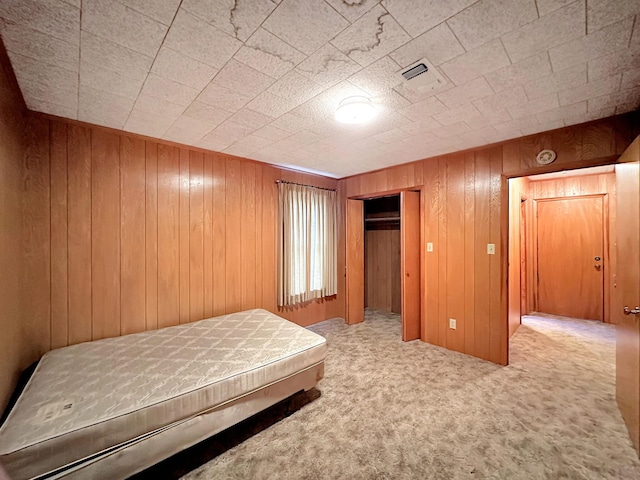 unfurnished bedroom with wood walls and carpet