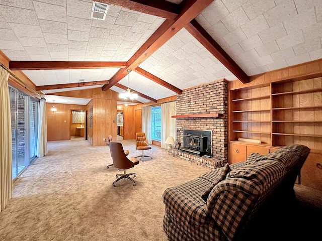 carpeted living room featuring a wood stove, wood walls, and vaulted ceiling with beams