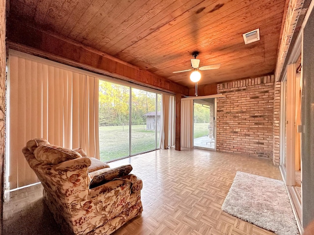 living area featuring wooden ceiling, wooden walls, ceiling fan, brick wall, and light parquet flooring