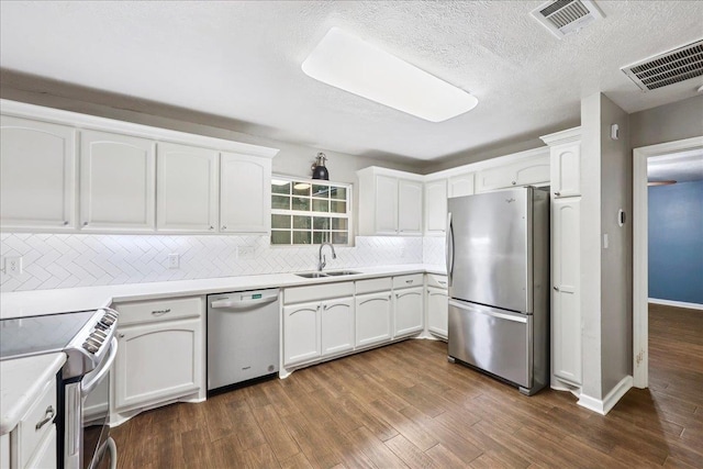 16 Briarcliff Ln, Lumberton, TX 77657 - kitchen featuring stainless steel appliances, decorative backsplash, white cabinets, dark wood-type flooring, and a textured ceiling