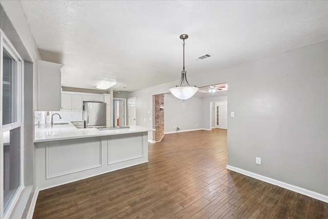 16 Briarcliff Ln, Lumberton, TX 77657 - kitchen featuring freestanding refrigerator, a peninsula, light countertops, white cabinets, and dark wood-style floors