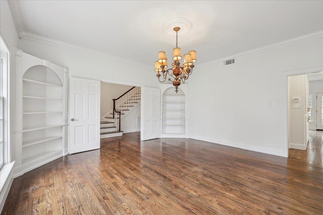 unfurnished room featuring built in shelves, dark wood-style flooring, baseboards, ornamental molding, and stairway