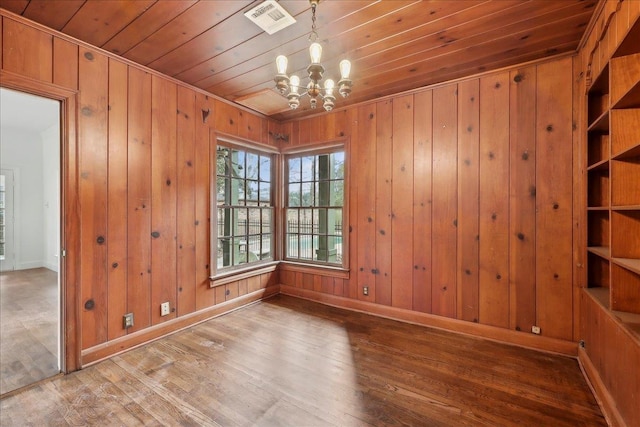 spare room featuring baseboards, visible vents, wooden ceiling, wood finished floors, and an inviting chandelier