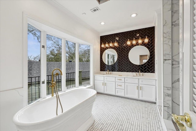 full bath with double vanity, a freestanding tub, tile walls, and crown molding