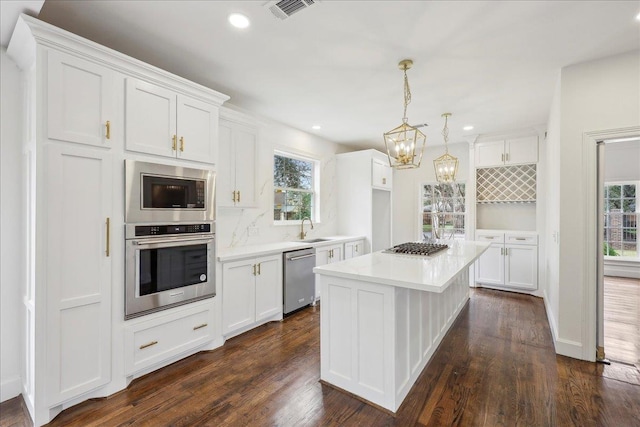 kitchen with a sink, stainless steel appliances, light countertops, and white cabinets