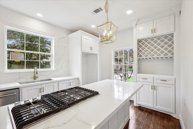 kitchen featuring plenty of natural light, hanging light fixtures, white cabinetry, stainless steel gas cooktop, and a sink