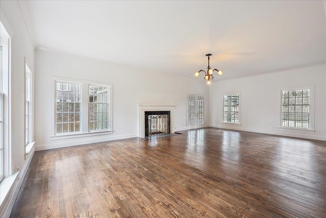 unfurnished living room featuring baseboards, a fireplace with flush hearth, dark wood-type flooring, crown molding, and a notable chandelier