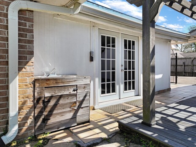 wooden terrace featuring french doors, a patio, and fence