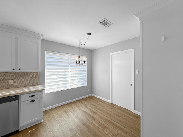 unfurnished dining area with light wood-style floors, a chandelier, and baseboards