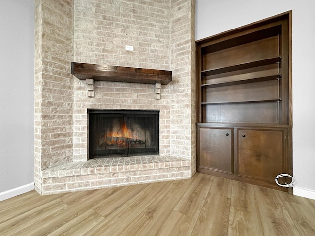 unfurnished living room with wood finished floors, baseboards, and a fireplace