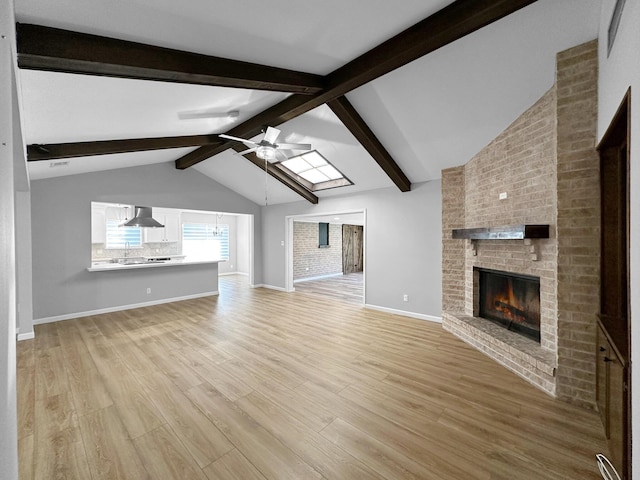 unfurnished living room with a brick fireplace, light wood-style floors, ceiling fan, and baseboards