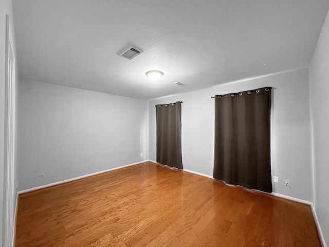 spare room featuring wood finished floors and baseboards