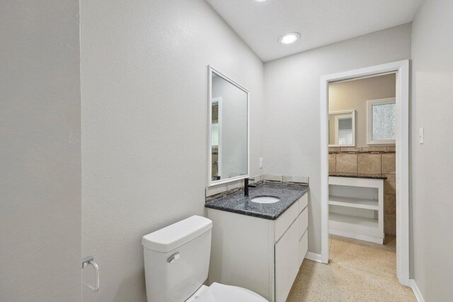 bathroom with toilet, speckled floor, and vanity