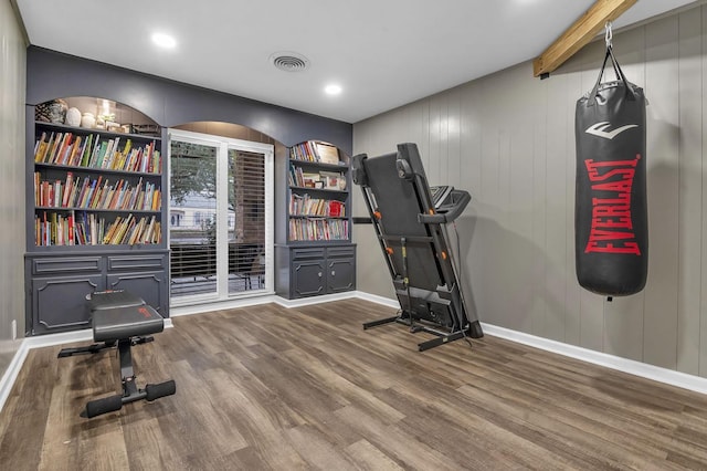 exercise room featuring hardwood / wood-style floors and built in shelves