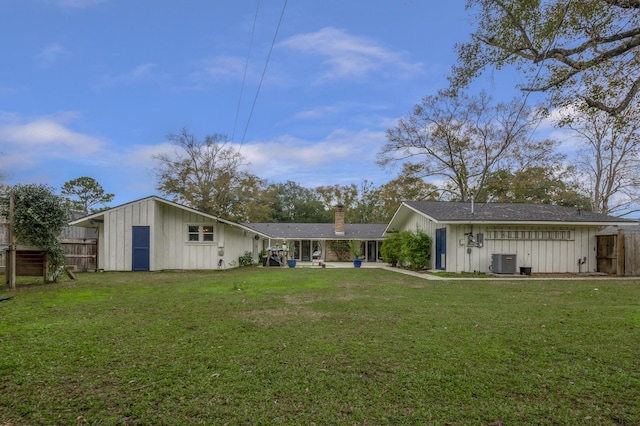 rear view of property with central AC and a lawn