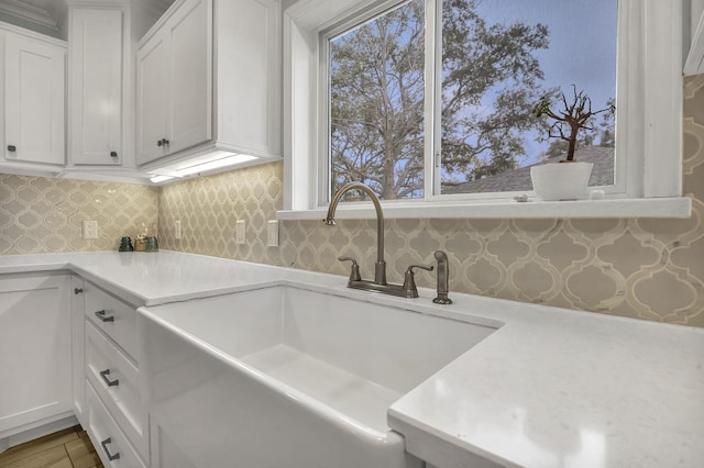 kitchen with sink, white cabinets, and backsplash