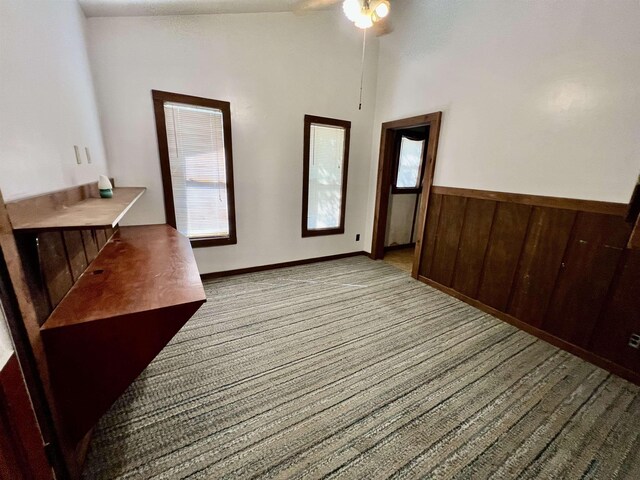 357 Hawks, Kountze, TX 77625 - unfurnished dining area featuring carpet flooring, lofted ceiling, ceiling fan, a wainscoted wall, and wooden walls