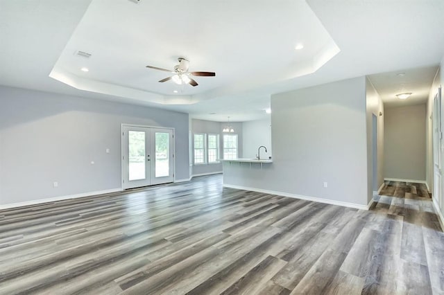 unfurnished living room featuring french doors, wood-type flooring, sink, and a tray ceiling