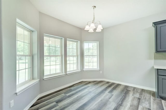 unfurnished dining area with an inviting chandelier and light wood-type flooring