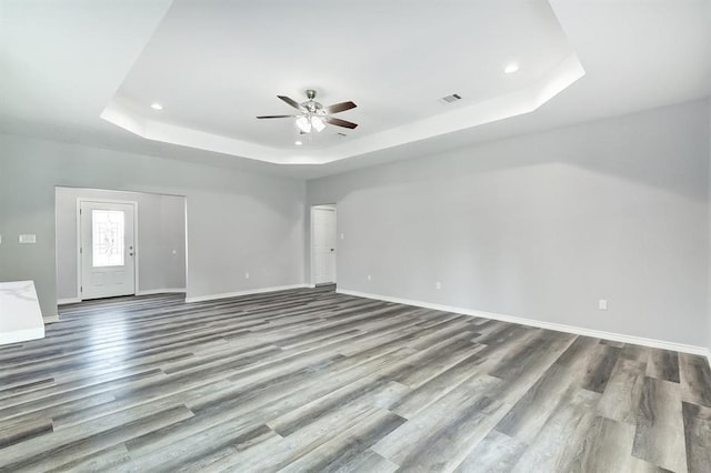 unfurnished room featuring a tray ceiling, wood-type flooring, and ceiling fan