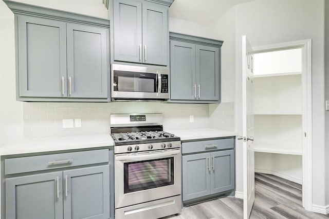 kitchen with appliances with stainless steel finishes, light hardwood / wood-style floors, and gray cabinetry