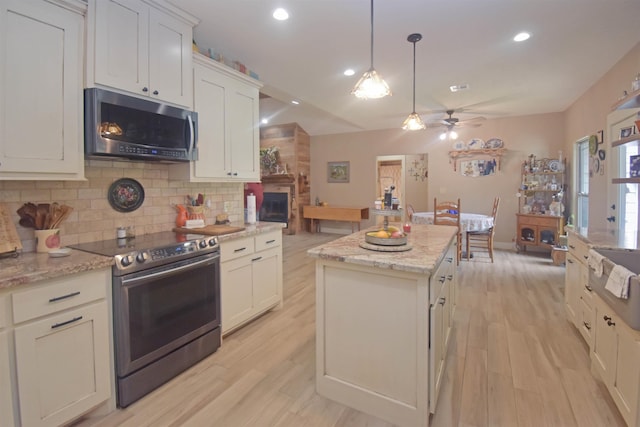 115 Pr 5250, Warren, TX 77664 - kitchen with stainless steel appliances, a center island, backsplash, a ceiling fan, and light wood finished floors