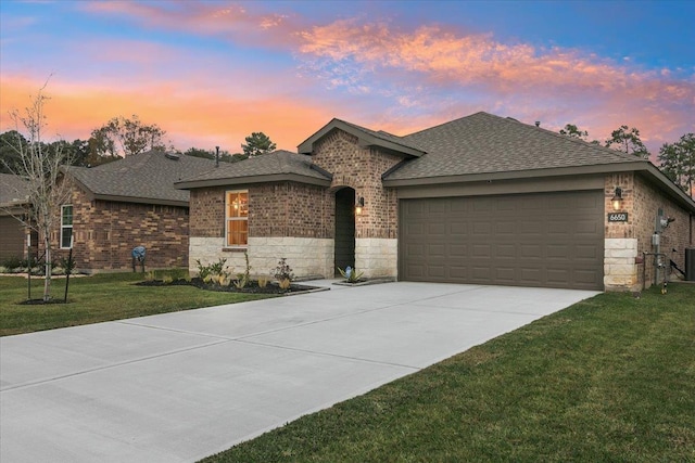 ranch-style house with a shingled roof, brick siding, driveway, and a front lawn