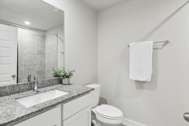 bathroom featuring vanity, toilet, and a tile shower