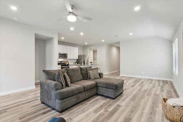 living room featuring ceiling fan, lofted ceiling, and light wood-type flooring