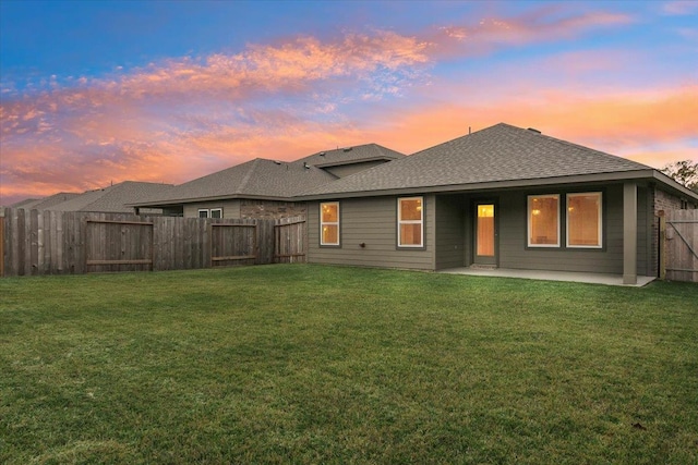 back house at dusk with a yard and a patio area