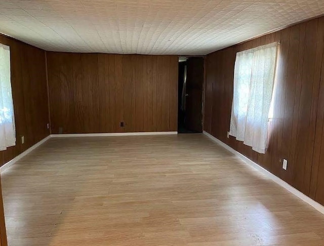 spare room featuring wooden walls and light hardwood / wood-style floors