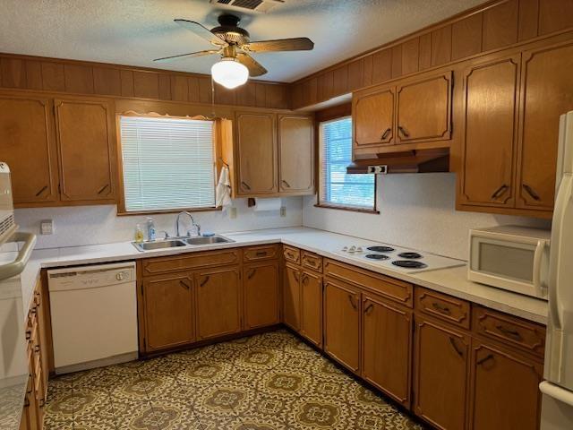 kitchen featuring a textured ceiling, ceiling fan, sink, and white appliances