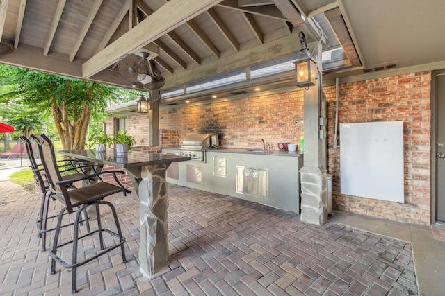 view of patio with an outdoor kitchen, a wet bar, and a grill