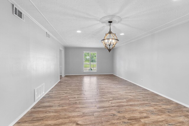 spare room with ornamental molding, a textured ceiling, hardwood / wood-style flooring, and a notable chandelier