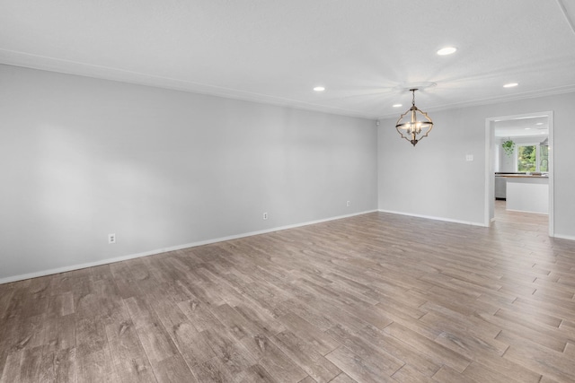 spare room with light hardwood / wood-style flooring and an inviting chandelier