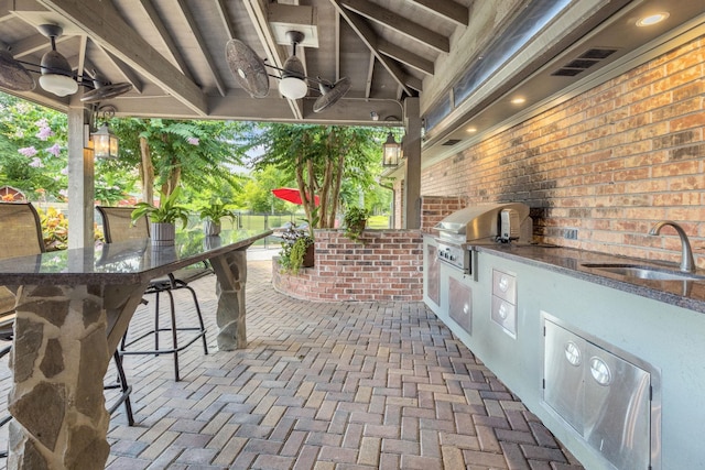 view of patio / terrace featuring area for grilling, ceiling fan, and a wet bar