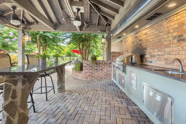 view of patio / terrace featuring area for grilling, ceiling fan, and a wet bar