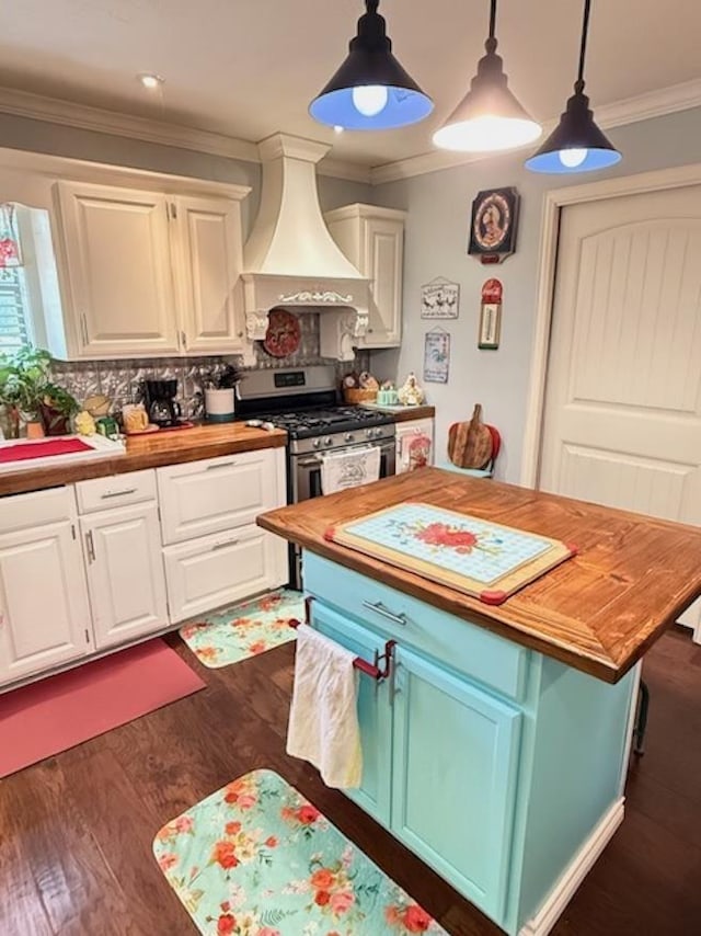 215 Wildwood Dr, Village Mills, TX 77663 - kitchen with butcher block counters, custom exhaust hood, stainless steel range with gas stovetop, and white cabinets