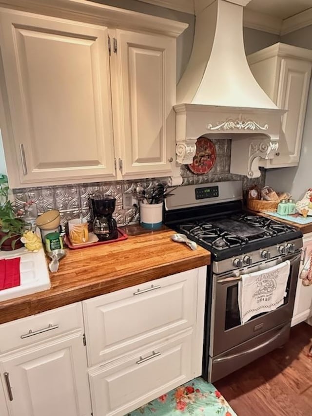 215 Wildwood Dr, Village Mills, TX 77663 - kitchen with custom exhaust hood, ornamental molding, stainless steel gas range oven, butcher block counters, and wood finished floors