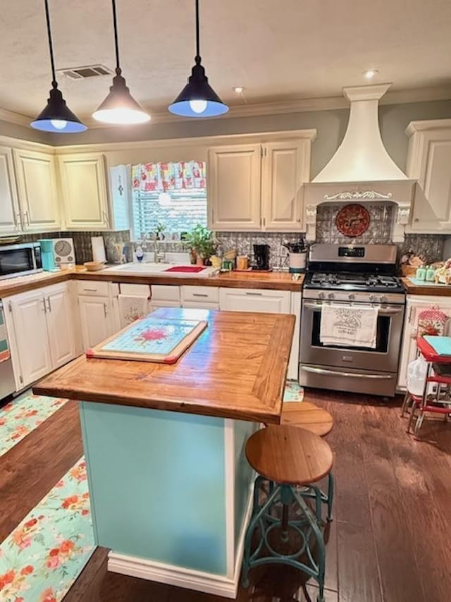 215 Wildwood Dr, Village Mills, TX 77663 - kitchen with ornamental molding, wood counters, premium range hood, visible vents, and stainless steel appliances