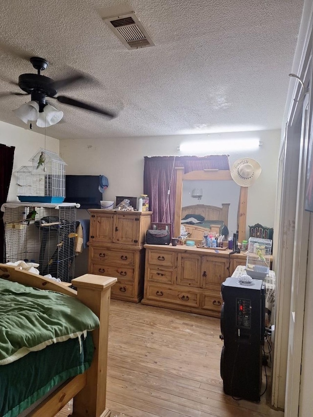 bedroom with a textured ceiling, light hardwood / wood-style flooring, and ceiling fan